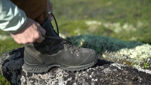 A traveler ties his shoelaces on his hiking shoes.