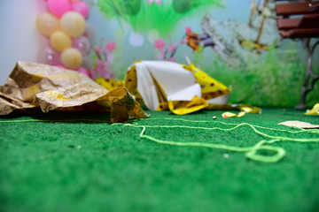 torn wrapping paper on the floor, crumpled wrapping paper on the lawn, artificial grass, children's...