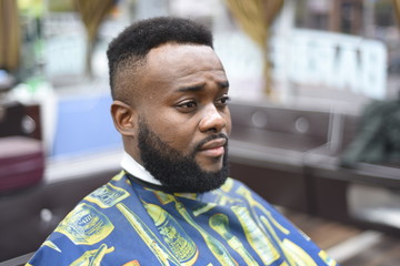 Black man in the Spanish barbershop. Cute black man makes a haircut in the African salon. Hair style. Haircut  for adults. 