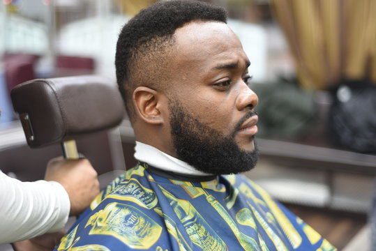 Black man in the Spanish barbershop. Cute black man makes a haircut in the African salon. Hair style. Haircut  for adults. 