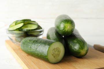 Board with cucumber on wooden background, close up