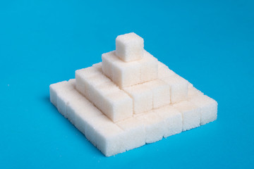 Sugar cubes pyramid on a blue background, creative food idea