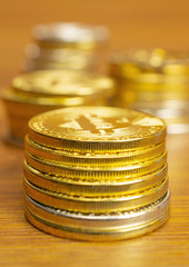 Rows and stacks of cryptocurrency coins on wooden table, vertical orientation blurred background for finance and business concept.