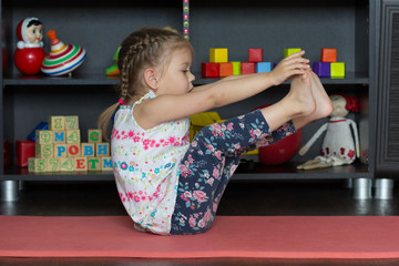 Little girl making boat yoga pose