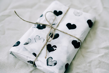 a gift wrapped in homemade wrapping paper with black hearts tied with jute thread for Valentine's...