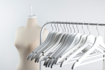 tailor mannequin and empty clothes hangers on white background