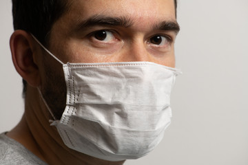 Dark-skinned young man wearing medical face mask, looking to the camera