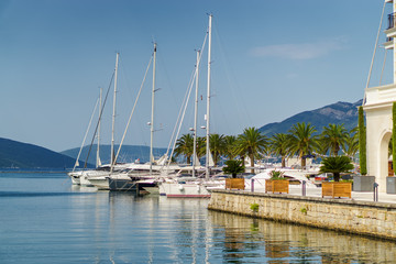 Fototapeta na wymiar Beautiful and cozy street cafe on the background of luxury yachts at the port of Tivat, Montenegro.