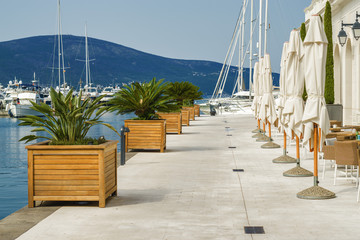 Beautiful and cozy street cafe on the background of luxury yachts at the port of Tivat, Montenegro.
