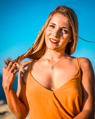 Lifestyle, a young smiling blonde in an orange dress in a photo shoot in nature