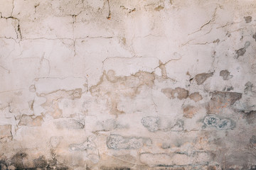 Rough textured cement concrete  wall with varying shades of gray, brown and cream with peeling layers