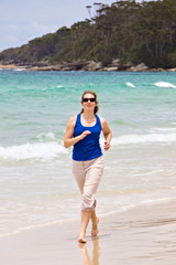 Fitness and lifestyle concept - young woman jogging and power walking on  a sunny beach