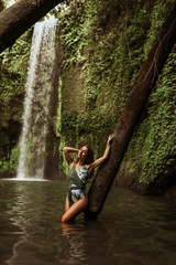 Fototapeta na wymiar Beautiful sexy girl under a waterfall in Indonesia.