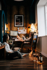 Young man booking tickets on website on modern laptop sitting on comfortable couch with girlfriend using home internet connection. Couple in love doing shopping together