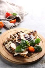 Grilled chicken and vegetables. Eggplant, mushrooms, tomatoes and herbs on a wooden board. Background image, copy space