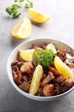 Mediterranean cuisine. Seafood with lemon and salad. Shrimp, octopus and squid in a light plate on a gray background. Background image, copy space