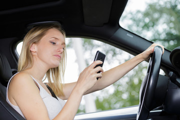 Fototapeta na wymiar woman in car texting on mobile phone whilst driving