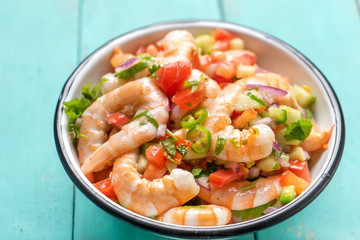 Mexican shrimp ceviche with tomato and serrano pepper on turquoise background