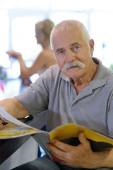 senior man looking at a catalogue at bar counter