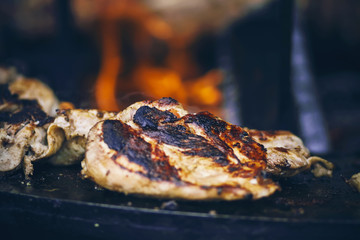 On an improvised grill, a fragrant, fat, juicy chicken fillet is fried against an open fire.