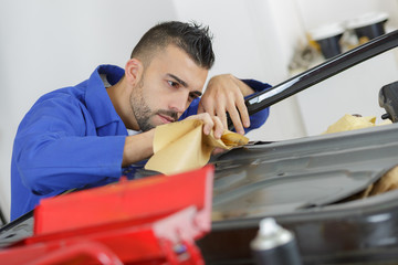 man carefully wiping a vehicle part