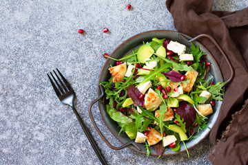 Salad with grilled chicken, avocado, brie cheese, arugula and pomegranate with vinaigrette dressing. Top view flat lay background. Copy space.
