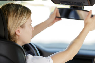 a woman is fixing the car rear mirror