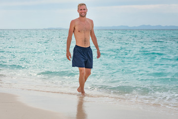 Portrait beau gosse charmant jeune homme caucasian blond aux yeux bleu joyeux confiance en soi séduisant chanceux charismatique européen heureux zen thailand île ko phi phi ko lanta plage sable blanc