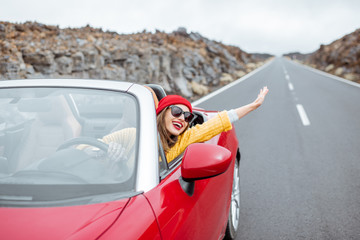 Portrait of a young woman traveling by convertible car on the picturesquare road on the volcanic...