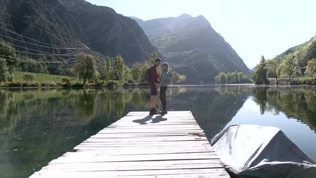 Video of two travel hikers in love kissing in front of the lake in mountain.