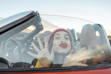 Portrait of a cute woman kissing through the car window while traveling by car