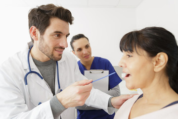 doctor checking mouth of mature female patient