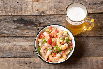Mexican shrimp ceviche with tomato and serrano pepper on wooden background