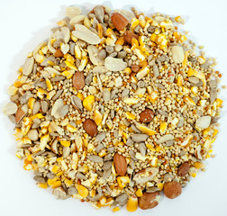 Circular pile of blended variety of birdseed on a white background.