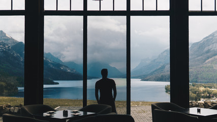 silhouette of man standing and looking at mountains