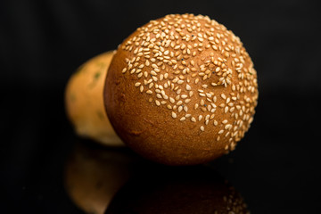 Bun with sesame seeds on a black background.