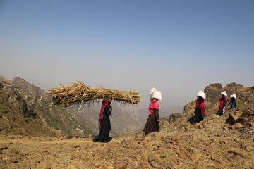 Yemeni children and women bring food and drink on bumpy mountain roads due to the siege and war on...
