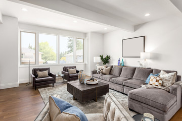 Beautiful living room in new home. Features large windows, bright interior, hardwood floors, couch, chairs, and coffee table