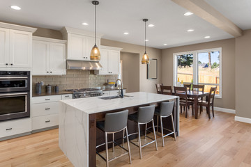 Kitchen in new home with stainless steel appliances, island, and pendant lights. Shows dining area.