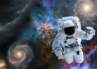 Astronaut near Mystic Mountain of Carina Nebula near far galaxies and stars. Science fiction. Elements of this image were furnished by NASA.