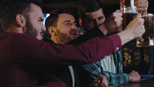 Closeup portrait in front of the camera charismatic three guys with chin in a pub drinking excited big glasses of beer and enjoying the evening time