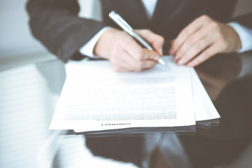 Unknown female hands with pen over document of contract. Agreement signing or business concept