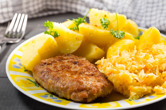 Minced pork cutlet served with potatoes and sauerkraut salad.