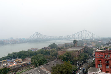 Aerial view Cityscape Howrah Bridge (Rabindra Setu) of Calcutta city life on Hooghly riverside near Burrabazar area on a foggy winter evening day. Kolkata West Bengal India South Asia Pac January 2020