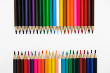 set of colored pencils arranged in a two rows horizontally opposite each other on a white background