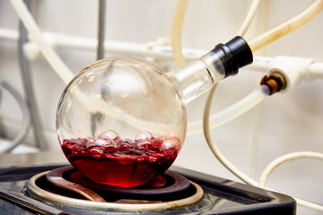 Red liquid boils in a round flask in the laboratory.