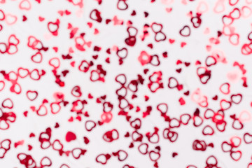 Fototapeta na wymiar Valentine's Day. Many shiny red hearts on a white background. Defocusing. Bokeh