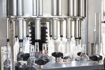 Factory for the production of alcoholic beverages. On the conveyor, vodka is bottled.