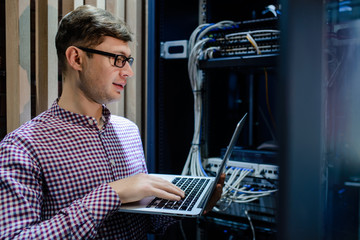 In the server room a technician/ It engineer/ hold the notebook
