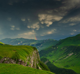 Fototapeta na wymiar Rainbow and incredible clouds over the valley in the mountains.